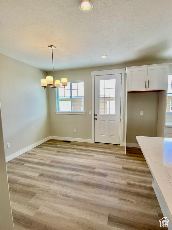 Interior space with light hardwood / wood-style flooring, a textured ceiling, and a chandelier