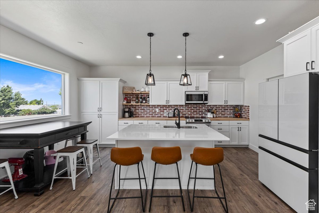 Kitchen with sink, dark hardwood / wood-style floors, a center island with sink, and stainless steel appliances