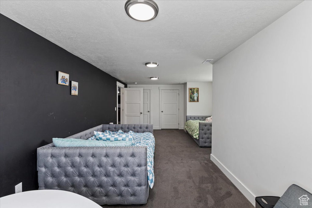 Bedroom with dark carpet and a textured ceiling