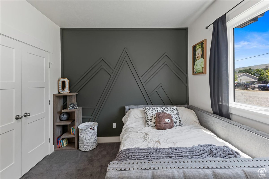 Bedroom with a closet and dark colored carpet