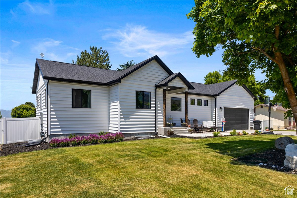 Ranch-style house featuring a garage and a front lawn