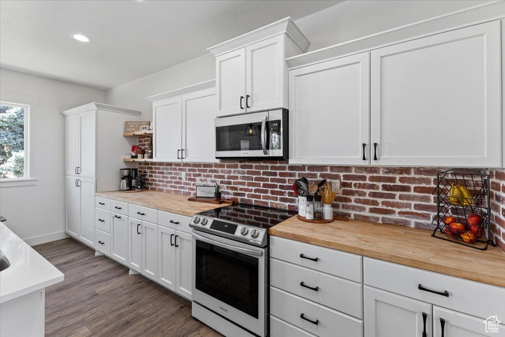 Kitchen with appliances with stainless steel finishes, butcher block counters, and white cabinets