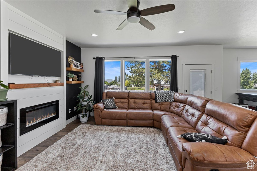 Living room with ceiling fan, dark hardwood / wood-style floors, and a fireplace