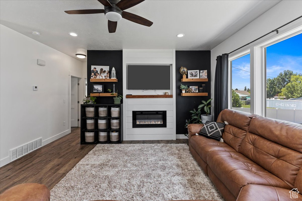 Living room featuring dark hardwood / wood-style floors, ceiling fan, and a fireplace