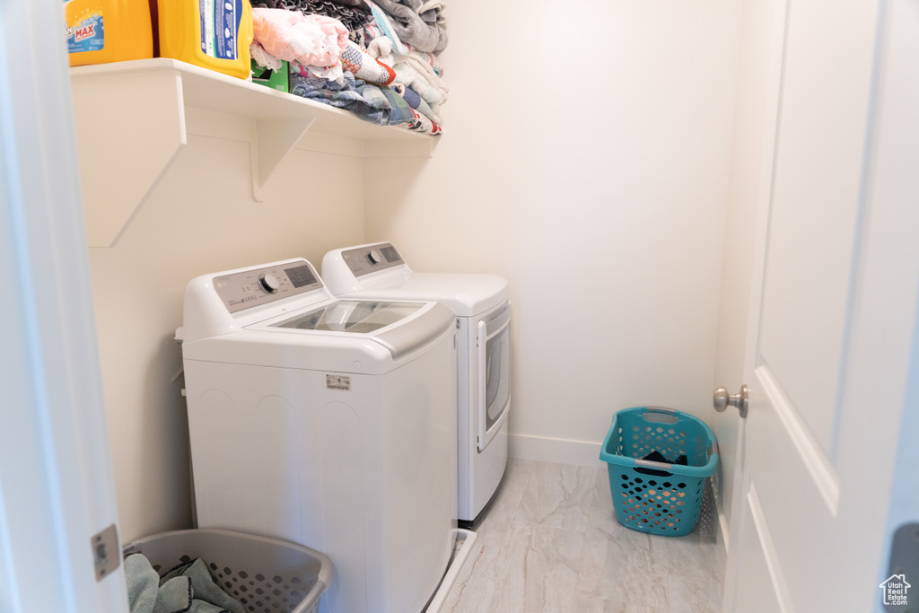 Clothes washing area with light tile flooring and independent washer and dryer