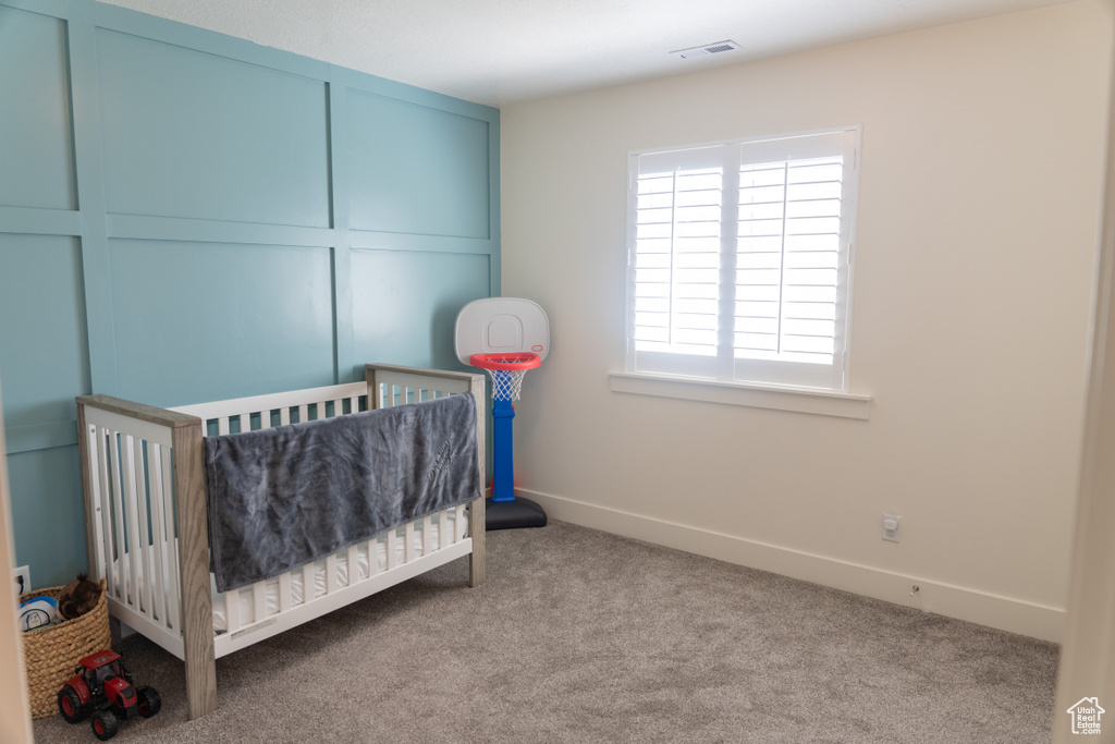 Bedroom with light carpet and a nursery area