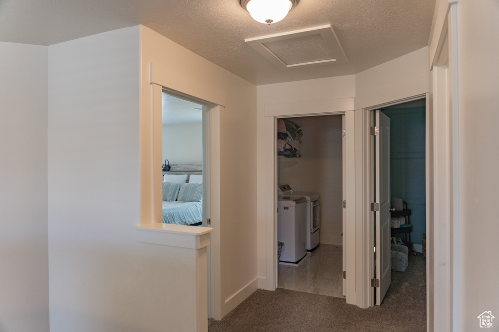 Hallway with washing machine and dryer and dark colored carpet