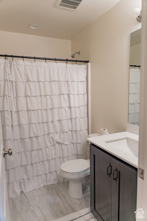 Bathroom with a textured ceiling, oversized vanity, and toilet