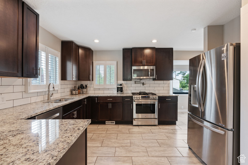 Kitchen with stainless steel appliances, sink, a wealth of natural light, and tasteful backsplash