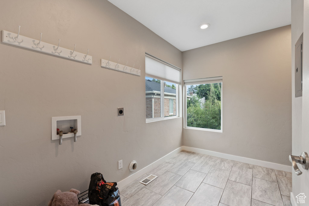 Clothes washing area with washer hookup, electric dryer hookup, and light tile floors