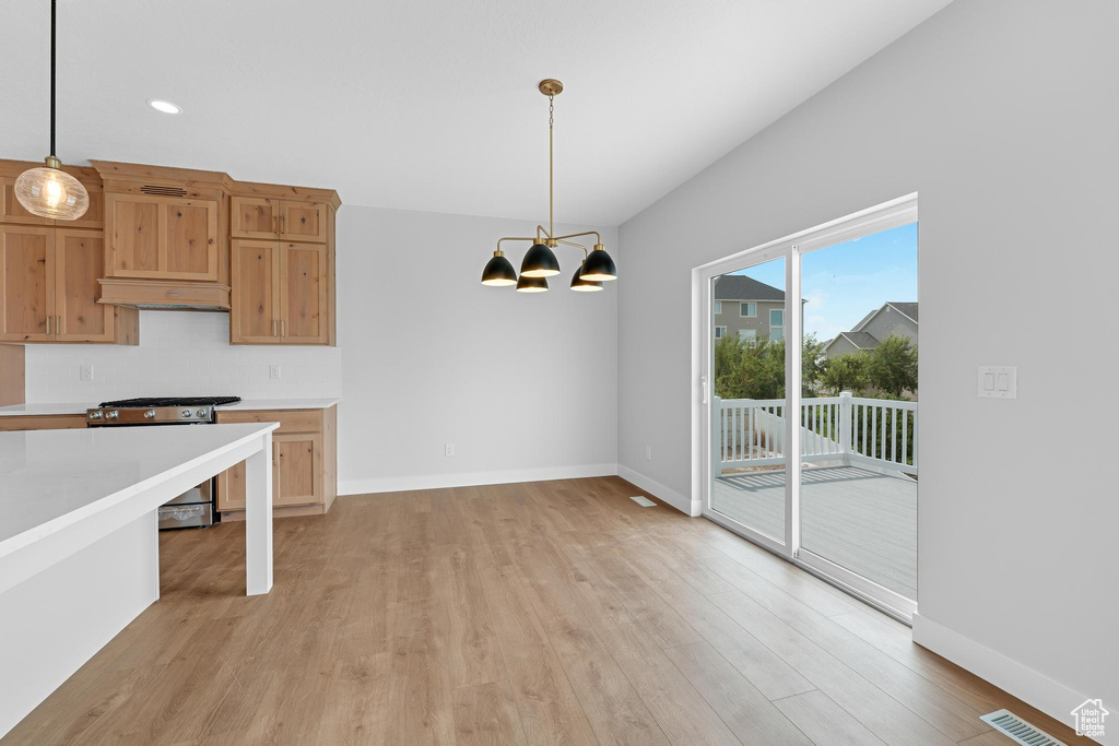 Kitchen featuring pendant lighting, premium range hood, a chandelier, stainless steel gas stove, and light wood-type flooring