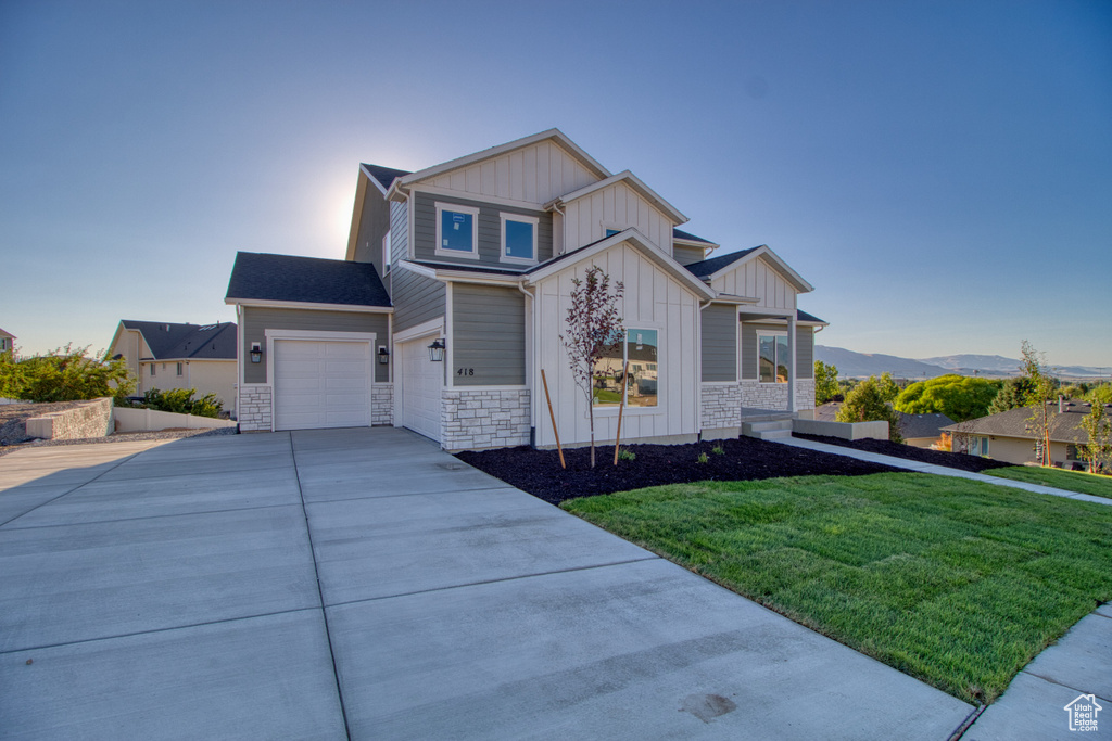 View of front of house with a mountain view, a garage, and a front lawn