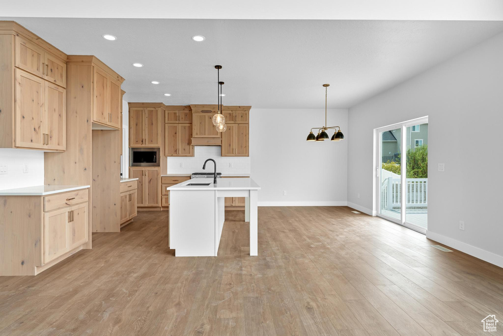 Kitchen featuring pendant lighting, a breakfast bar area, a kitchen island with sink, and light hardwood / wood-style flooring