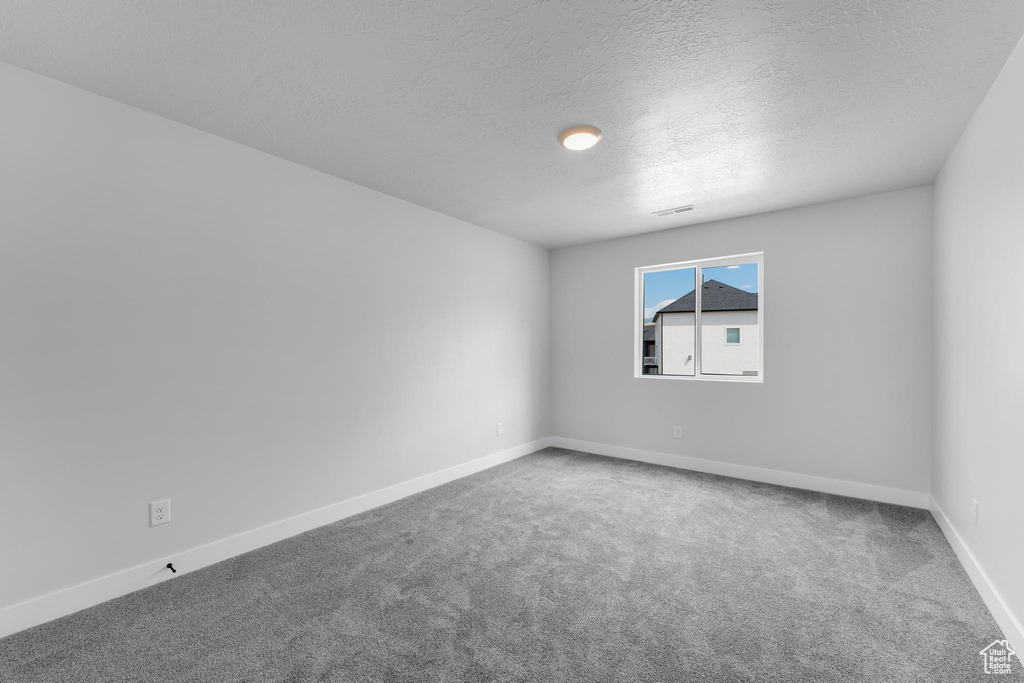 Spare room with a textured ceiling and carpet