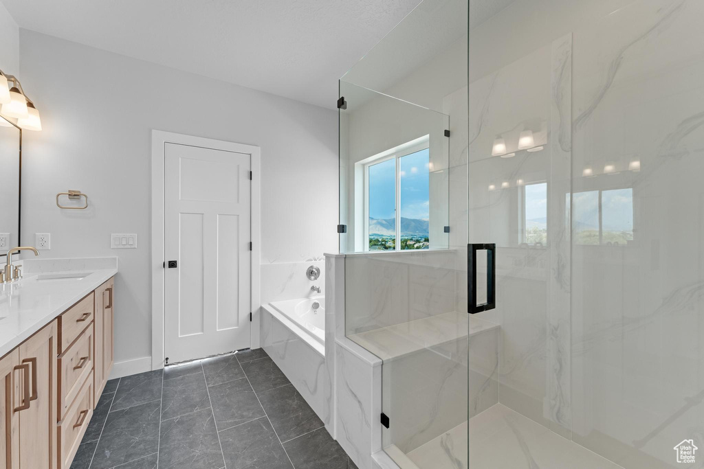 Bathroom with tile patterned floors, shower with separate bathtub, and vanity