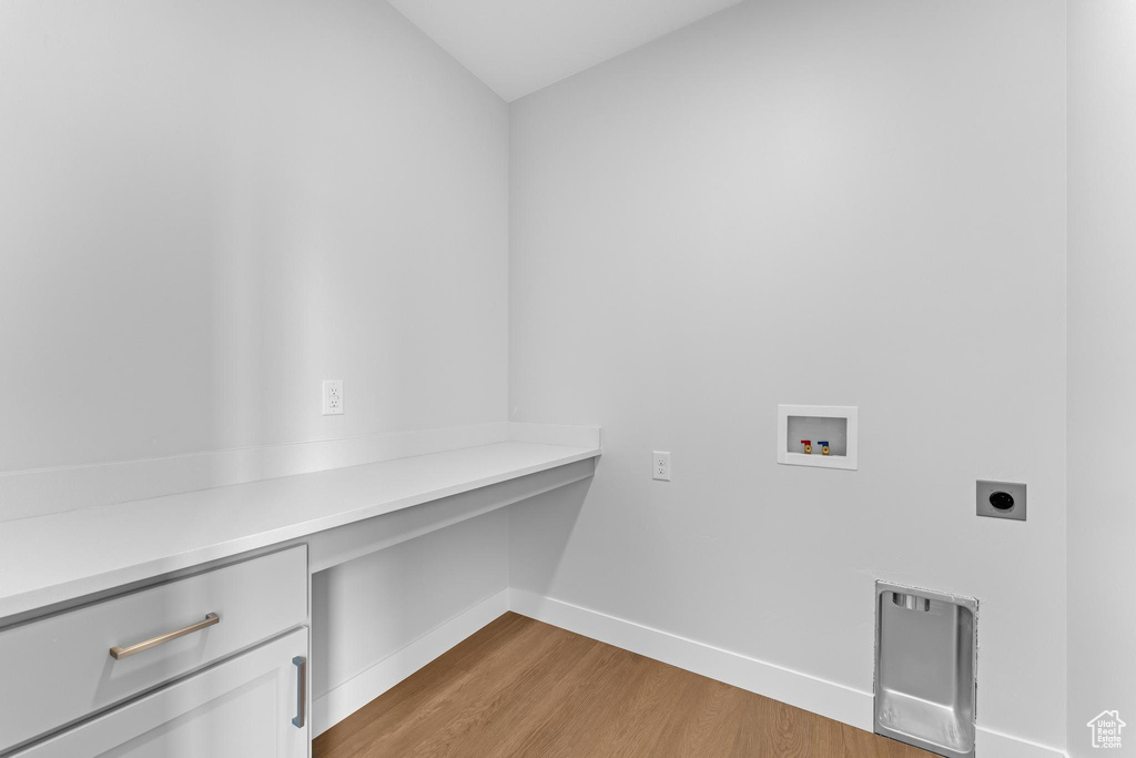 Washroom featuring hookup for a washing machine, light hardwood / wood-style flooring, cabinets, and hookup for an electric dryer