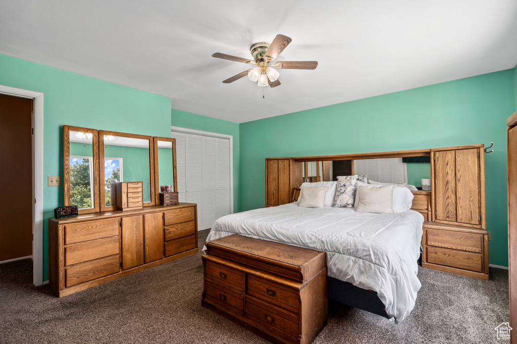 Bedroom with ceiling fan, a closet, and dark colored carpet