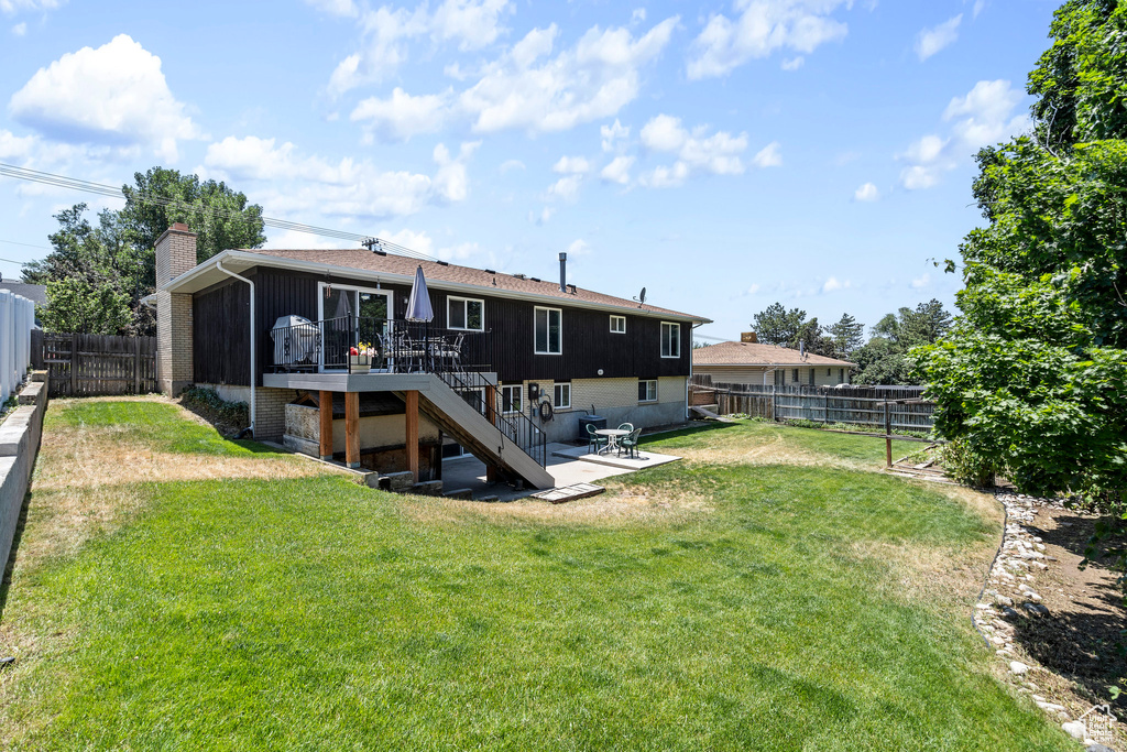 Back of house featuring a wooden deck and a lawn