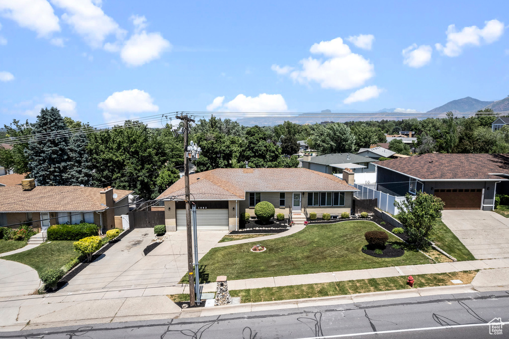 Ranch-style home with a garage, a mountain view, and a front lawn