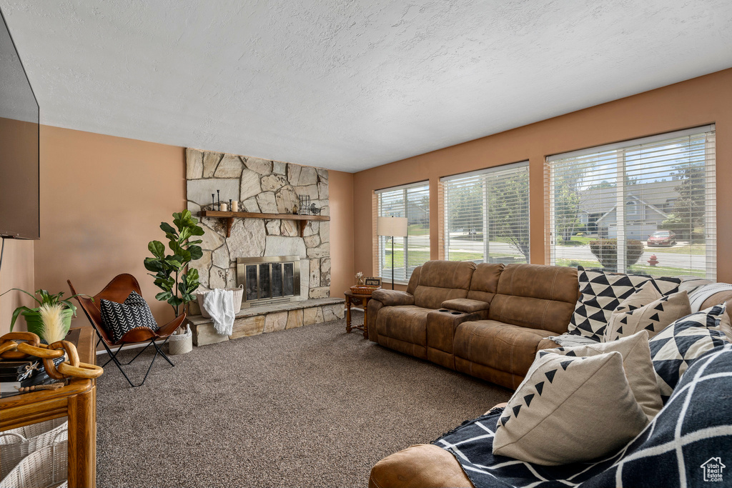 Living room with a stone fireplace, a textured ceiling, and carpet