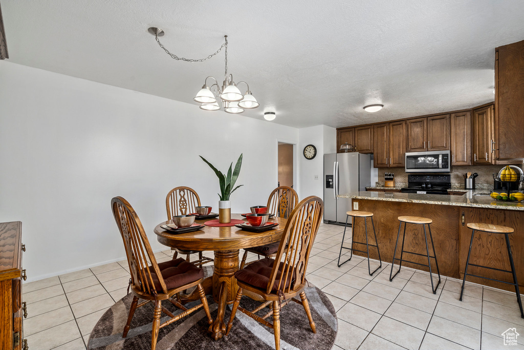 Dining area with a notable chandelier, sink, and light tile floors