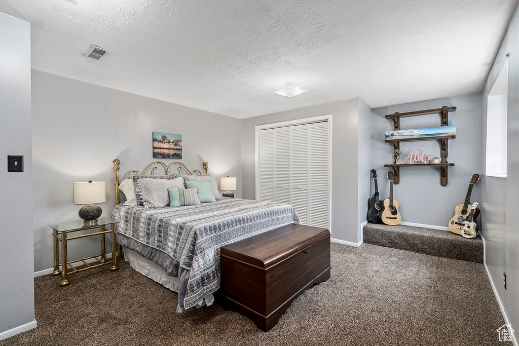 Bedroom with a closet, a textured ceiling, and carpet floors