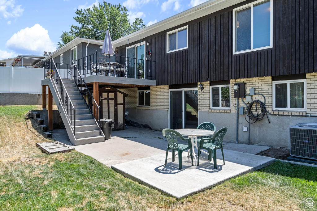 Back of house with central AC, a lawn, a patio area, and a wooden deck