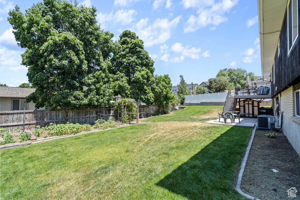 View of yard featuring a deck, central AC, and a patio