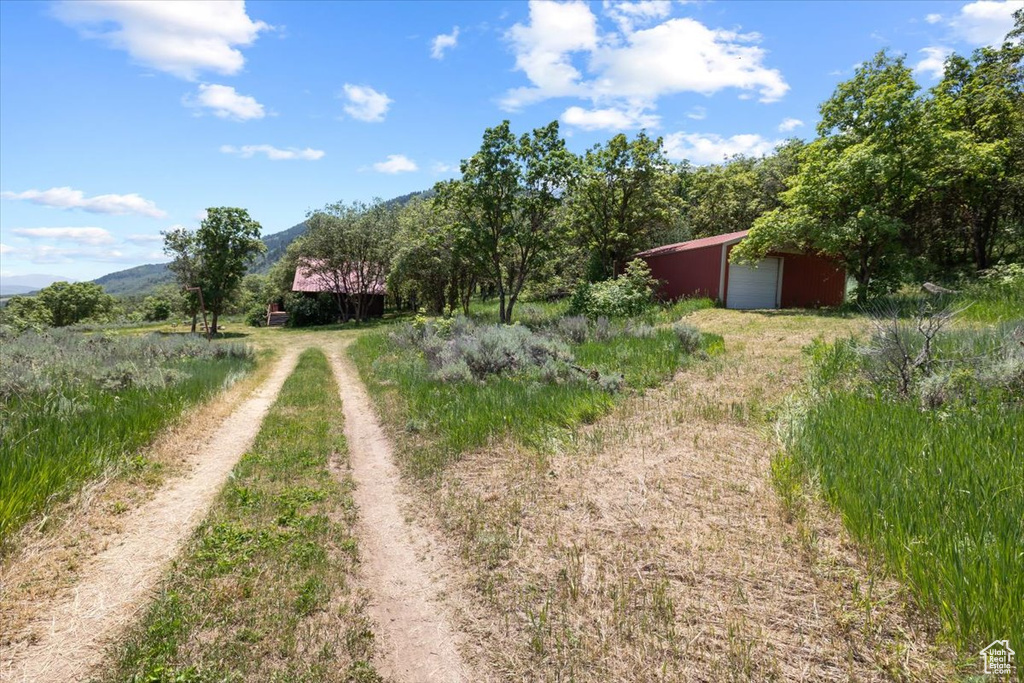 View of yard featuring an outdoor structure, a mountain view, a rural view, and a garage