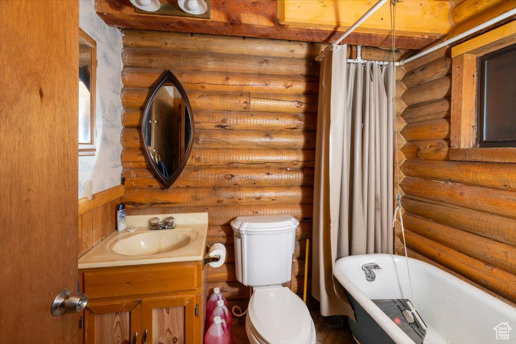 Bathroom featuring toilet, vanity, log walls, and a washtub