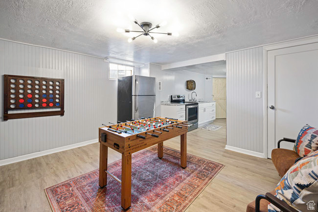 Playroom with sink, a textured ceiling, and light wood-type flooring