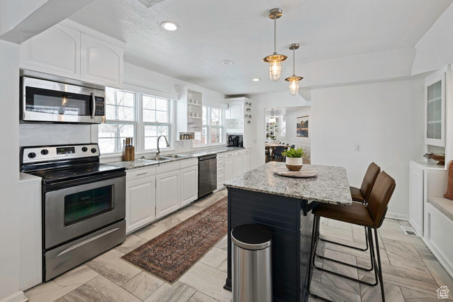 Kitchen featuring stainless steel appliances, white cabinetry, and a kitchen island