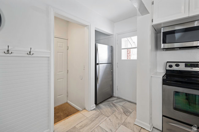 Kitchen with light tile floors, white cabinetry, and appliances with stainless steel finishes