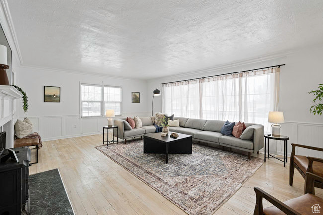 Living room featuring a textured ceiling, light hardwood / wood-style flooring, and crown molding