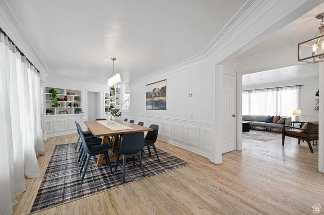 Dining room featuring a notable chandelier, ornamental molding, light hardwood / wood-style flooring, and built in shelves