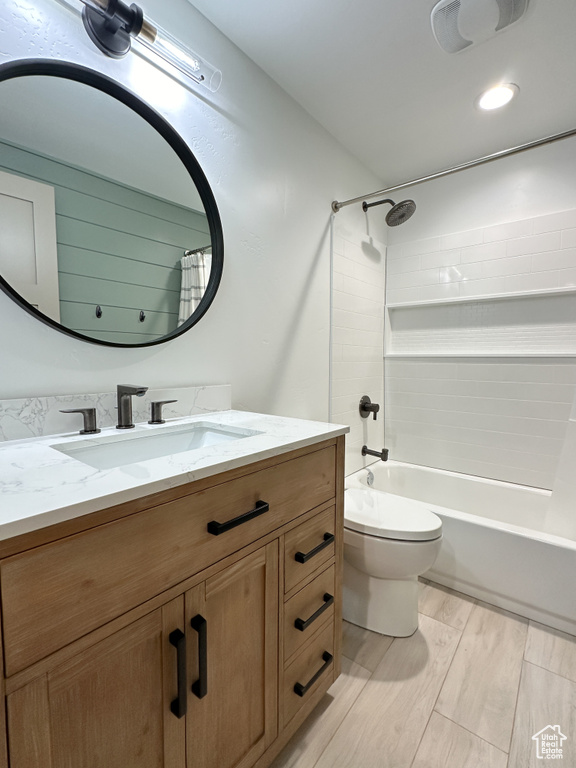 Full bathroom featuring vanity, tiled shower / bath combo, wood-type flooring, and toilet