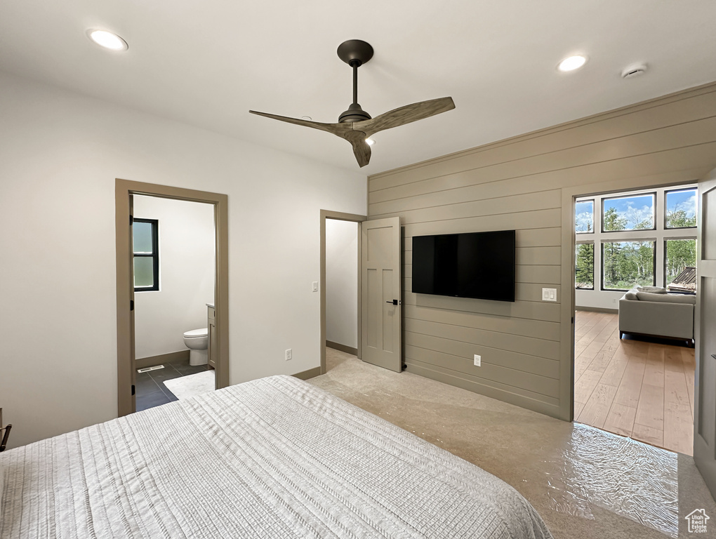 Bedroom with ensuite bath, ceiling fan, and hardwood / wood-style floors