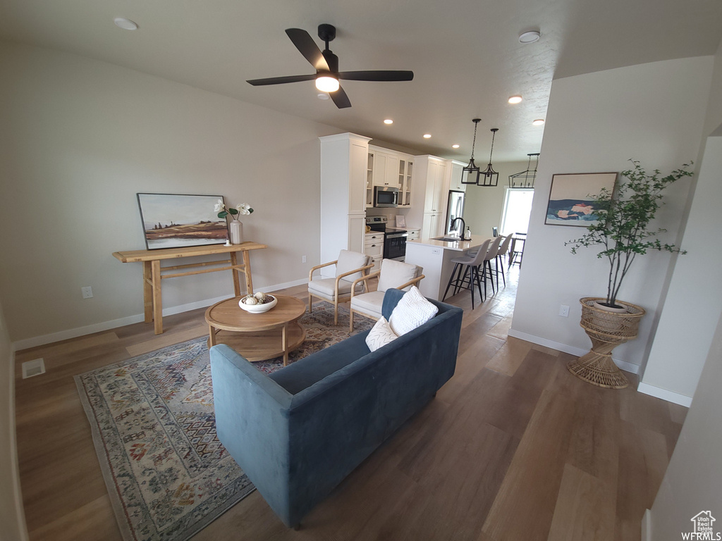 Living room featuring ceiling fan, sink, and dark wood-type flooring