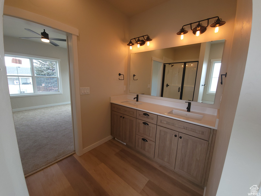 Bathroom with dual sinks, ceiling fan, oversized vanity, wood-type flooring, and walk in shower