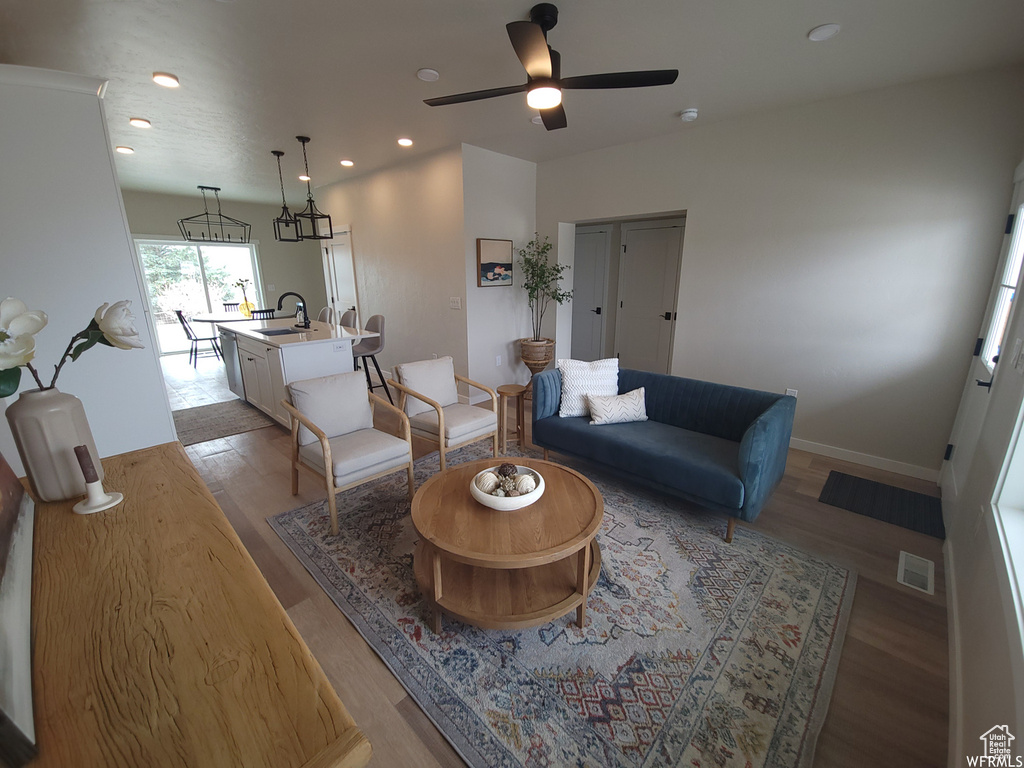 Living room featuring ceiling fan, light wood-type flooring, and sink