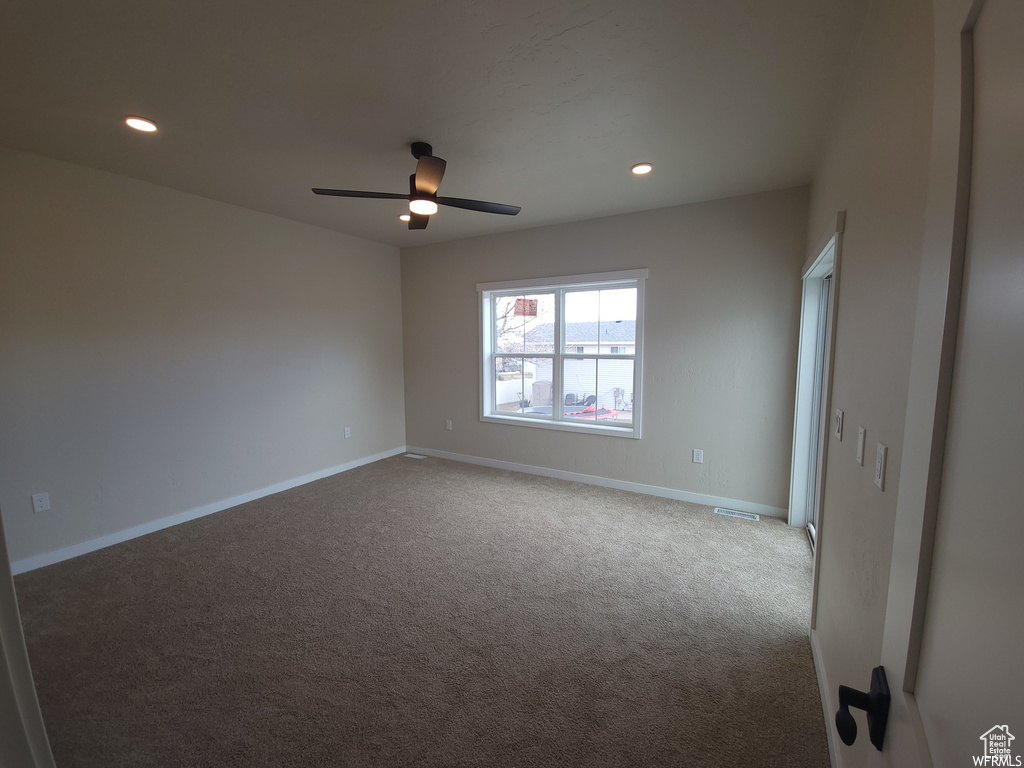 Carpeted empty room featuring ceiling fan