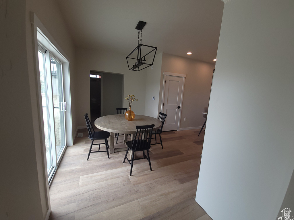 Dining area with a healthy amount of sunlight, light wood-type flooring, and a chandelier