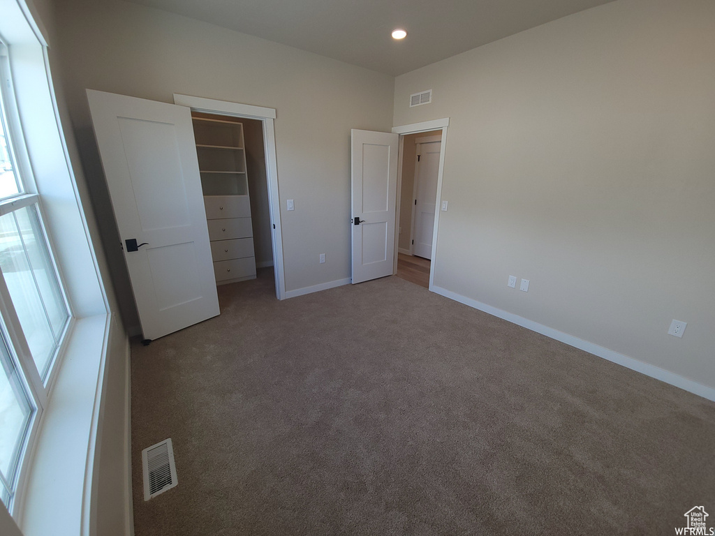 Unfurnished bedroom with carpet, a closet, and a spacious closet