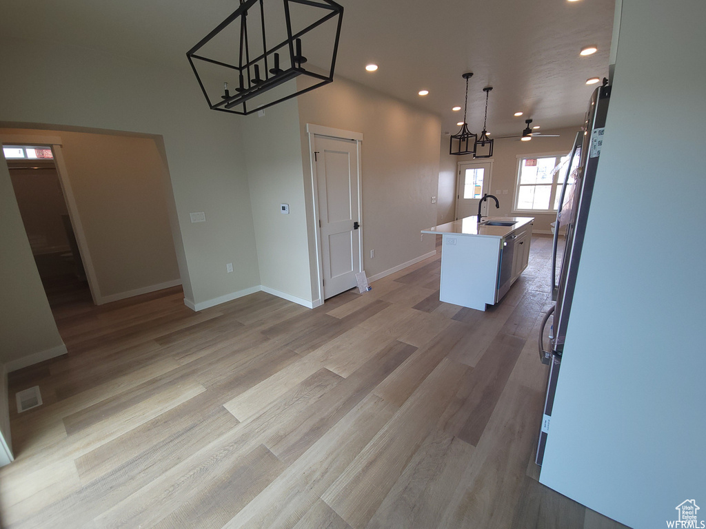 Kitchen featuring light hardwood / wood-style flooring, a kitchen island with sink, and pendant lighting