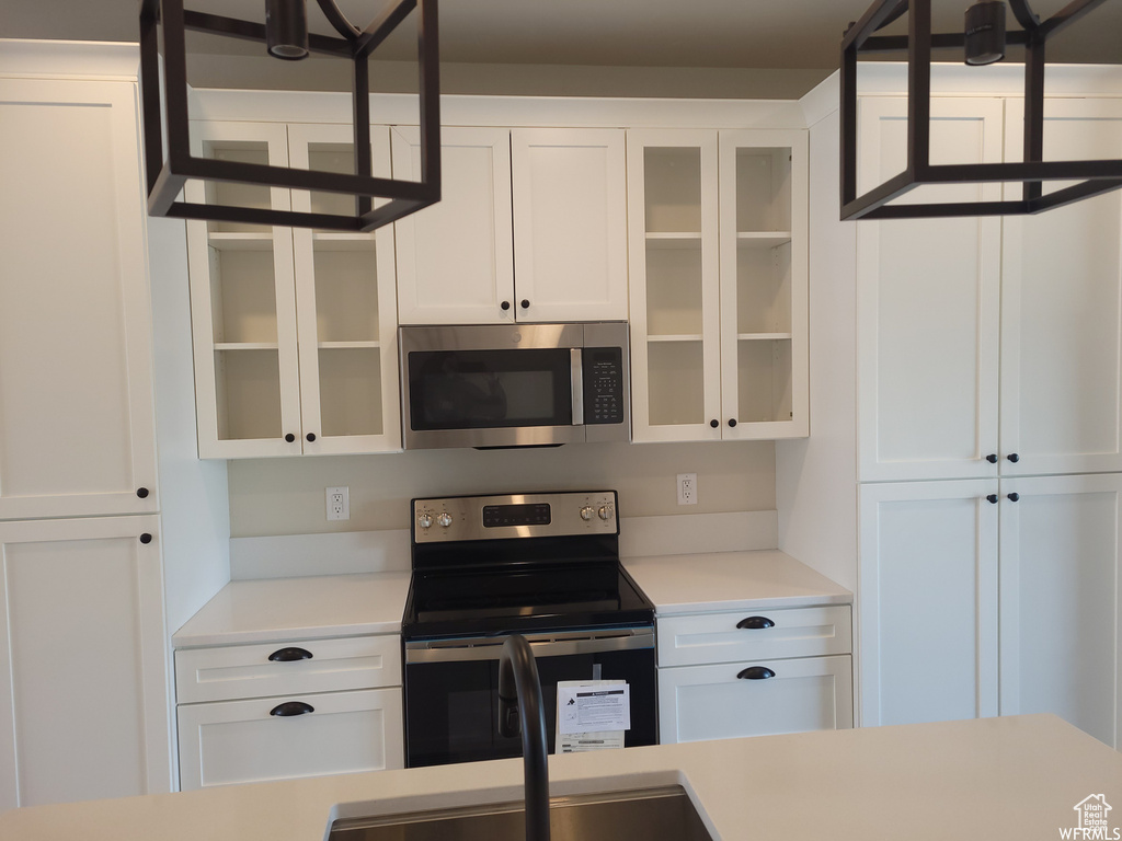 Kitchen with appliances with stainless steel finishes and white cabinetry