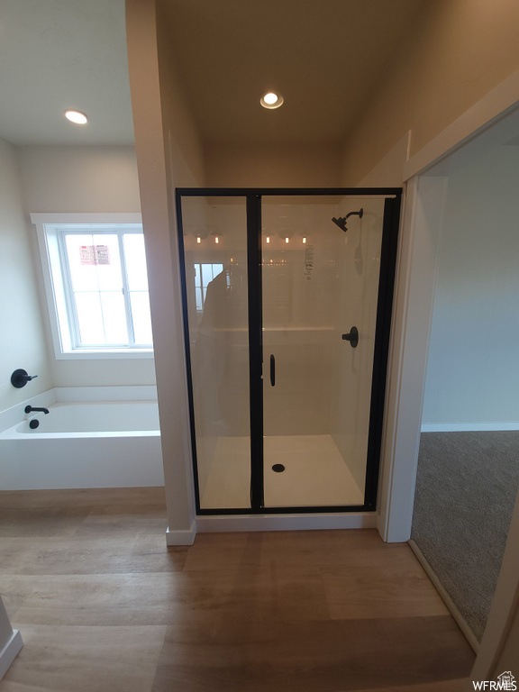 Bathroom with independent shower and bath and hardwood / wood-style floors