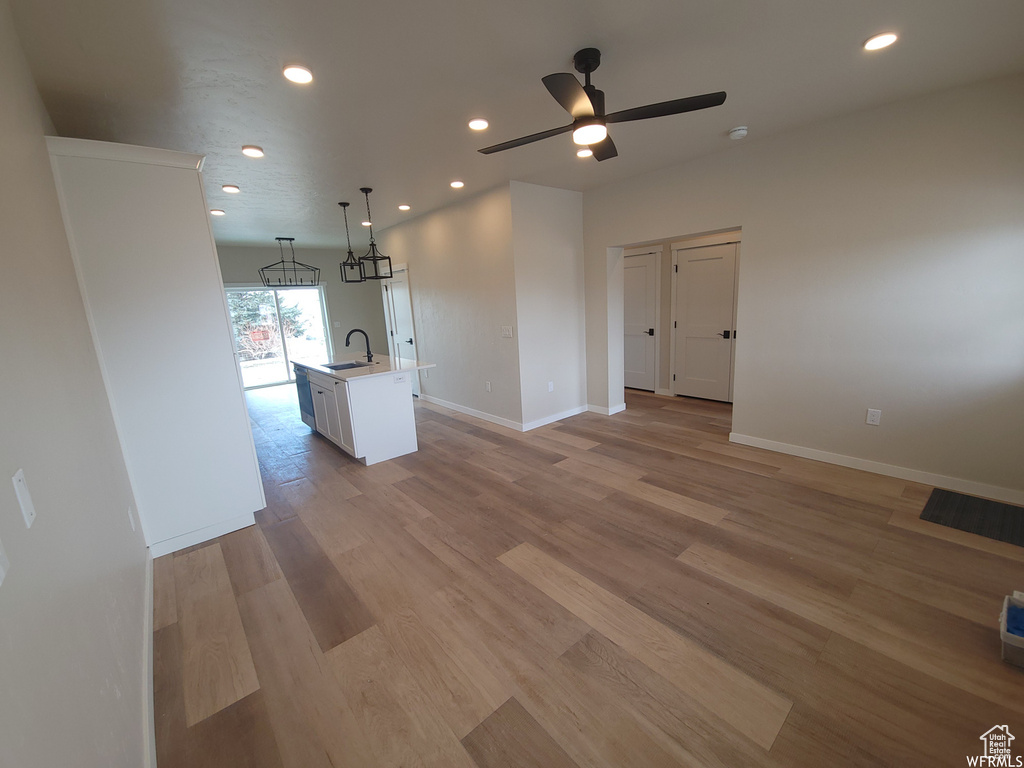 Unfurnished living room featuring sink, light wood-type flooring, and ceiling fan