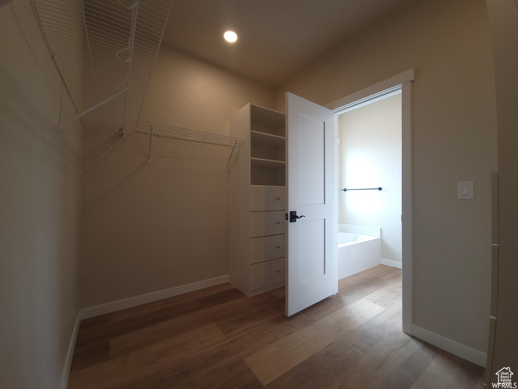 Walk in closet with hardwood / wood-style flooring