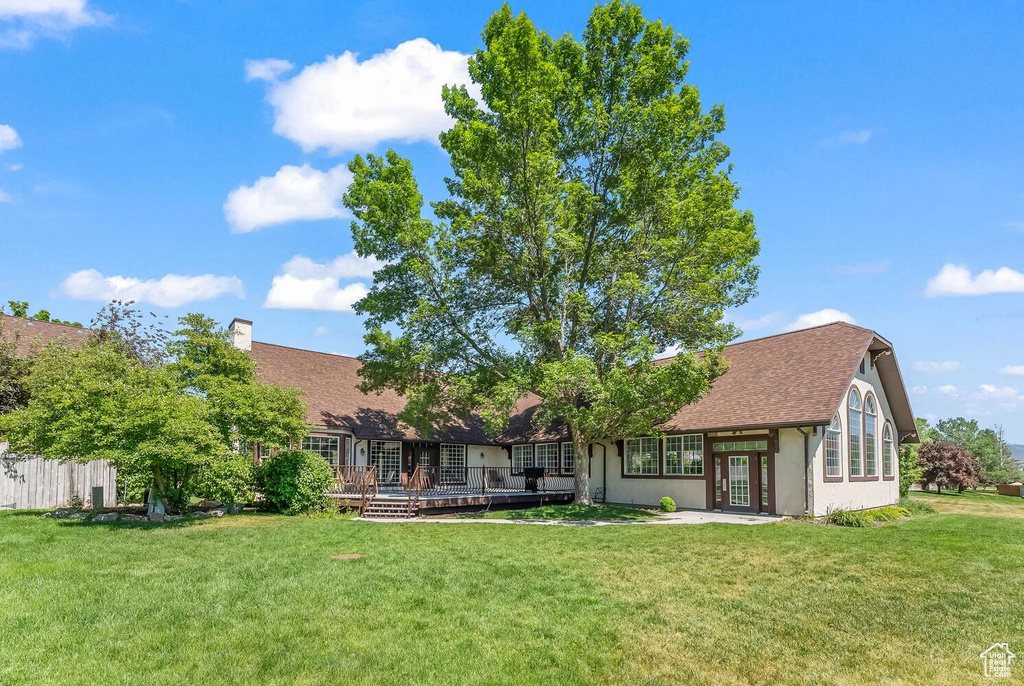 Back of property with french doors, a lawn, and a wooden deck