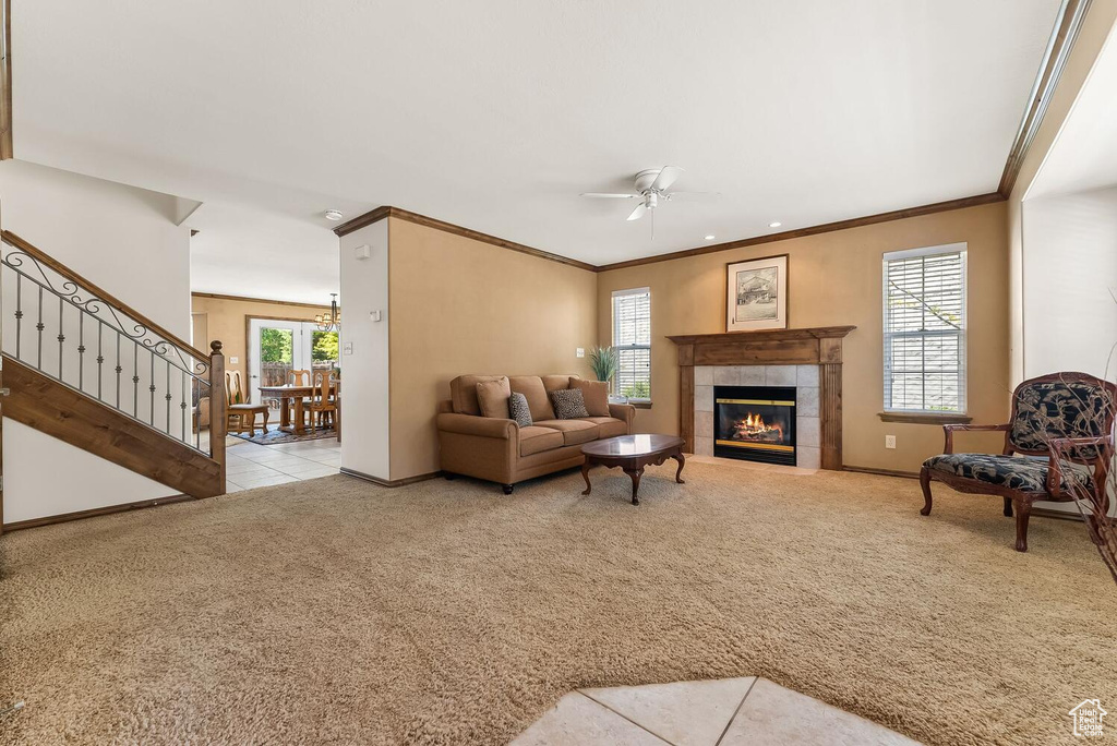 Living room with crown molding, ceiling fan, a fireplace, and light carpet